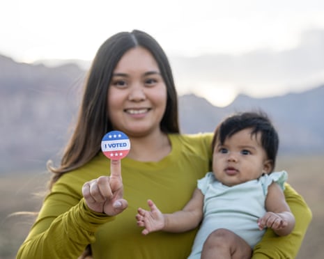 Young woman holding baby and an "I Voted" sticker