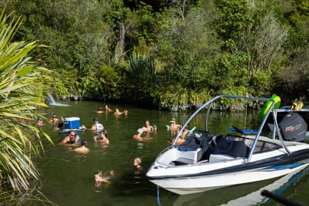 Locals enjoy a thermal pool at the head of a tributary to the Waikato River, near Taupo, Waikato, New Zealand.