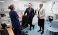Streeting and Dixon facing camera in GP surgery with woman in blue NHS uniform facing them