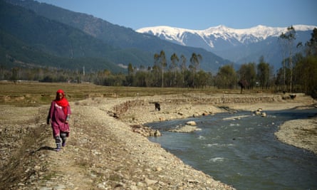 A Kashmiri villager walks past what used to be a pond holding drinking water in the village of Chandigam in the Lolab valley in the foothills of the northern Kashmir Himalayas, where glaciers are melting fast.