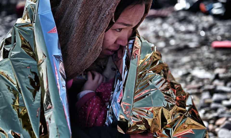 A woman hugs her child wrapped in a thermal blanket