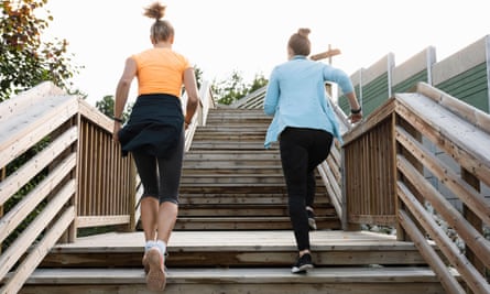 Two women jogging on the stairs outdoors.
