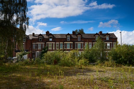 Row of terraced houses viewed from an overgrown patch of land and trees