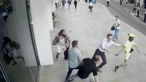 a man in yellow being tackled by members of the public