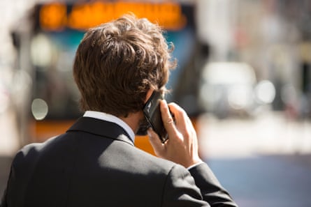 A man seen from behind holding a phone to his ear.