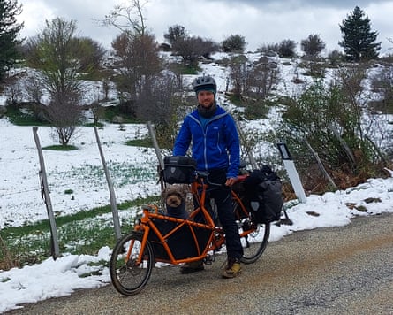 A man on a cargo bike with a dog in the storage compartment