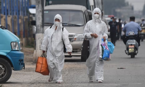 Women wearing protective suits walk near the closed Xinfadi market linked to the fresh cluster of coronavirus cases in Beijing.