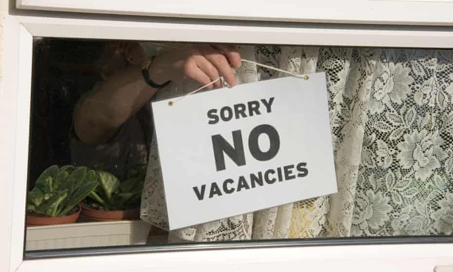 Close-up of person hanging No Vacancies sign on window