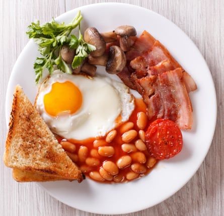 English breakfast: fried egg, bacon, beans and toast on a plate close-up. horizontal view from above