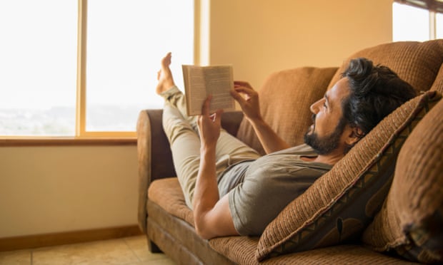 man reading book on sofa