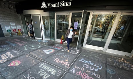 A woman exits Mount Sinai hospital, where messages of thanks to healthcare workers are written on the sidewalk, in New York City Tuesday.