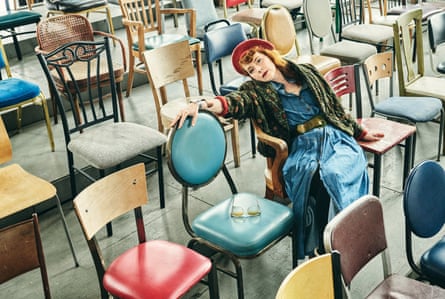 Melissa Auf der Maur in a room of different coloured chairs