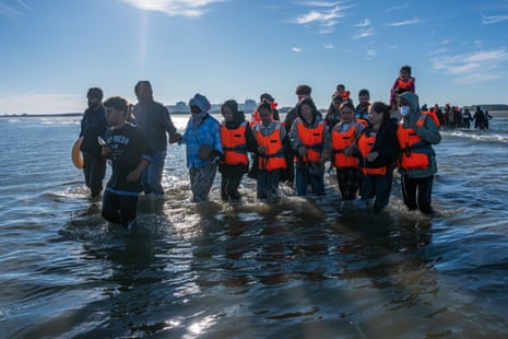 Migrants wade into the sea to board a dinghy to cross the English Channel on 25 August 2025 in Gravelines, France.