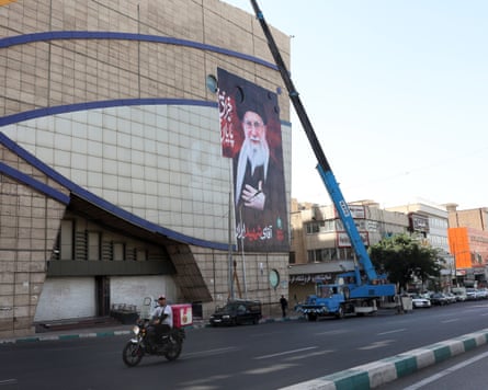 A crane is used to install a billboard of Khamenei on the side of a building
