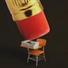 A giant pencil eraser hovers over a school desk covered with newspapers