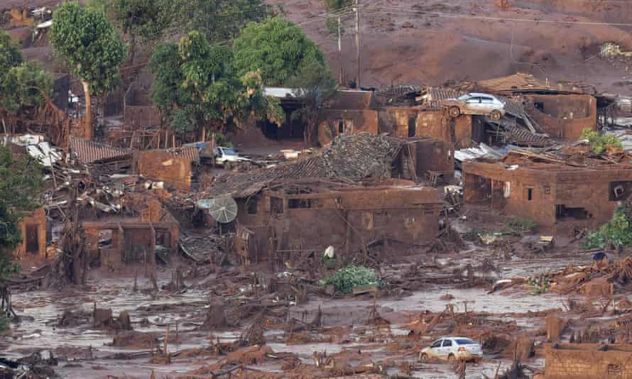 A village after a sea of red-brown mud inundated it. A care can be seen perched on a roof