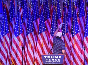 A man vacuums US national flags on the stage where Trump will speak at the New York Hilton Midtown hotel