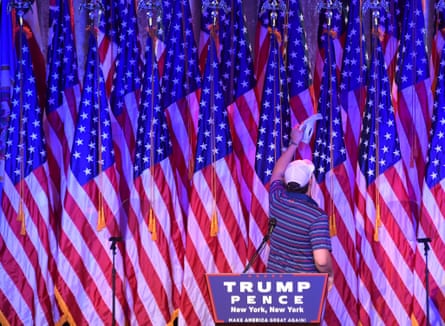 A man vacuums US flags on the stage where Donald Trump will speak later.