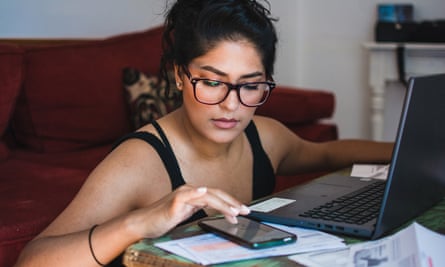 Latina woman working on her personal finances, sitting in her living room with her bank statements, bills and computer.