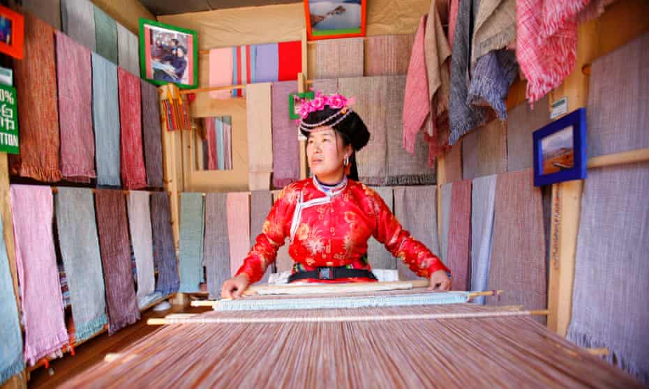 A Mosuo woman weaves with a loom at her shop in Lijiang, China.
