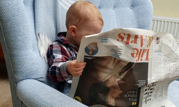 Southwold, UK. New Guardian reader (18 months old) copying Grandpa! Checking the brainteaser answers?