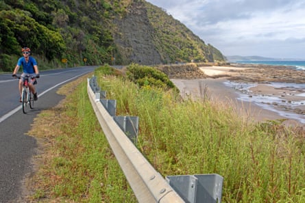 A cyclist riding on the Great Ocean Road along a coastline near Lorne, Victoria
