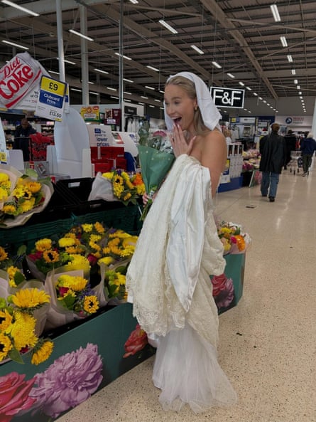 A young woman in a white wedding dress looking at flowers in the supermarket