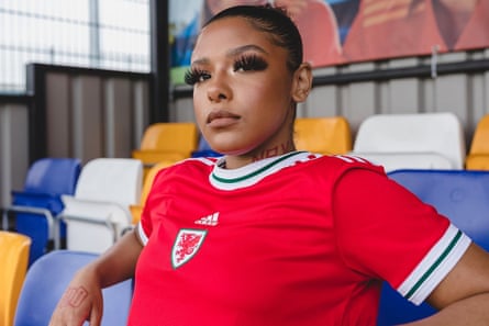 Juice Menace in a Welsh football top, sat on a football terrace