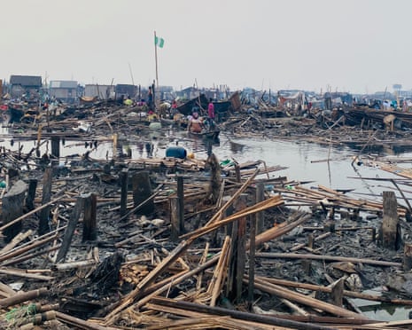 ‘They told us to leave. They didn’t tell us where to go’: the demolitions destroying homes and lives in Lagos A Nigerian flag flies above demolished homes in Makoko. People stand among the ruins and others are in canoes.