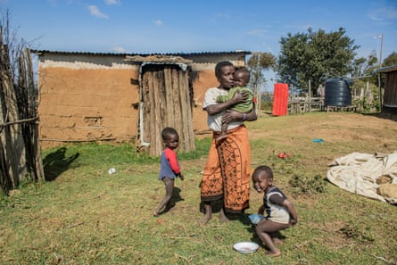 A Maasai woman in a farm yard playing with three young children