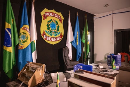 A table with a police logo on the wall behind with Brazilian and other flags either side of it