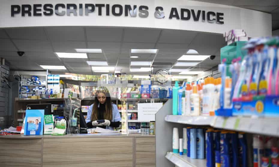 Medicine counter assistant working behind a screen in Copes Pharmacy in Streatham