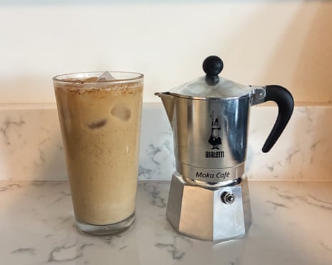 A cup of iced coffee next to a Moka pot