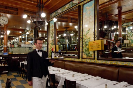 A formally dressed waiter in bow tie inside a brasserie in Paris.