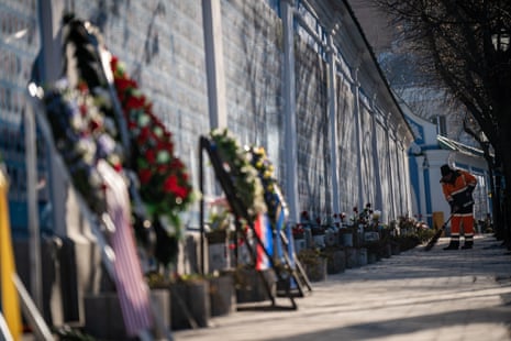 A city worker cleans along the Wall of Remembrance of the Fallen for Ukraine near Mykhailivska Square, Kyiv