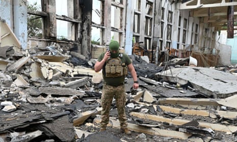 A Ukrainian serviceman amid the rubble of a building in Kharkiv