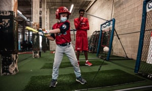 Javon Solomon, trained as a baseball “ambassador” for a nonprofit in Atlanta, looks on as Thomas Connelly takes a swing. He used to help support his family by selling bottles of water at freeway off-ramps.