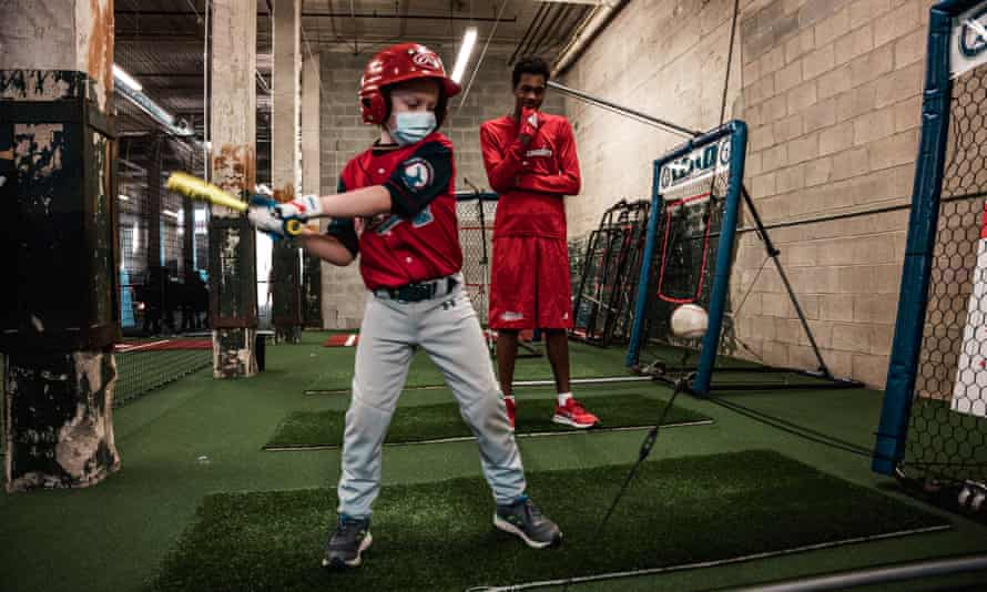 Javon Solomon, entrenado como “embajador” de béisbol para una organización sin fines de lucro en Atlanta, observa cómo Thomas Connelly hace un swing.  Solía ​​ayudar a mantener a su familia vendiendo botellas de agua en las rampas de salida de la autopista.