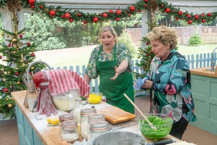 Siobhan McSweeney gestures animatedly beside Sandi Toksvig at a Bake Off kitchen counter