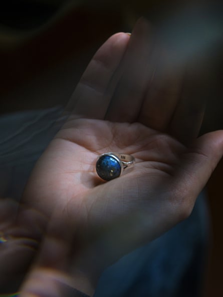 A ring with blue stone in the palm of a hand.
