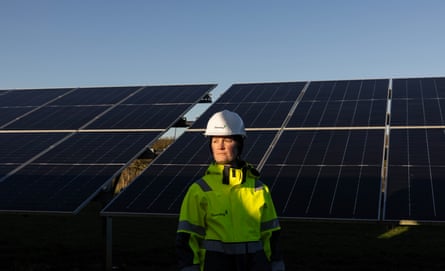 Saffron Hooper-Kay, who manages Whitecross solar farm in Lincolnshire, UK, standing in front of solar panels in white hard hat and hi-vis jacket