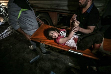 Palestinian Civil Defence men carry a wounded girl after an Israeli air strike in Gaza City, 16 May.