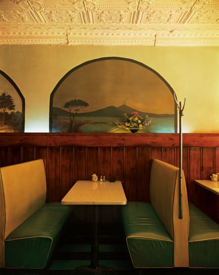 A vinyl-seated booth in an Italian restaurant with an ornate plaster ceiling and murals on the walls