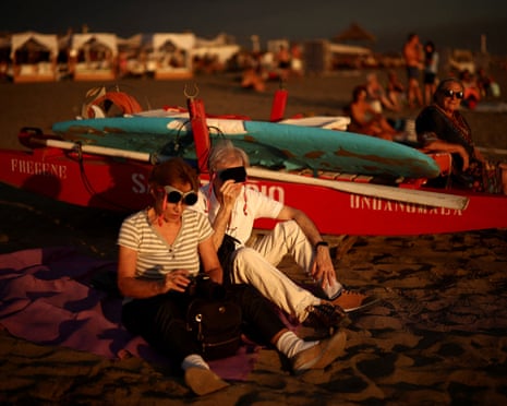 Beachgoers watch a solar eclipse as the moon partially covers the sun and briefly dims the afternoon light along the coast of Fregene, near Rome, Italy.