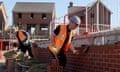 Two male bricklayers working on the wall of a new-build house