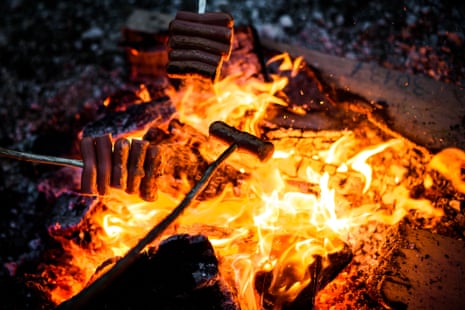 Cooking sausages over an open camp fire