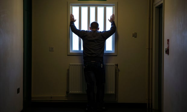 A prisoner staring out of a window down one of the corridors of the enhanced wing at HMP Portland prison in Dorset.