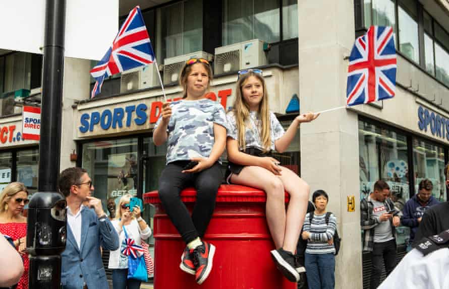 Amy and Malie from Pembrokeshire, Wales, watch the events from atop a red postbox.
