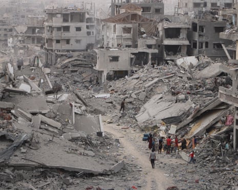 Palestinians, carrying what belongings they could with them, returning to the Shuja'iyya neighbourhood after the ceasefire agreement came into effect are seen walking among buildings destroyed in attacks by the Israeli army on 16 October 2025 in Gaza City, Gaza