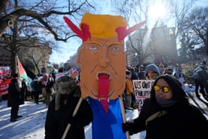 a person holds a poster with a drawing of Donald Trump sticking his tongue out and with horns